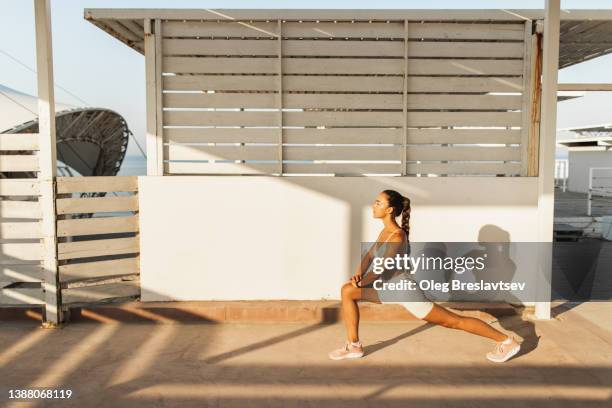 woman doing lunges, warming up exercises before endurance interval workout or running. athletic body - warming up for exercise stock pictures, royalty-free photos & images