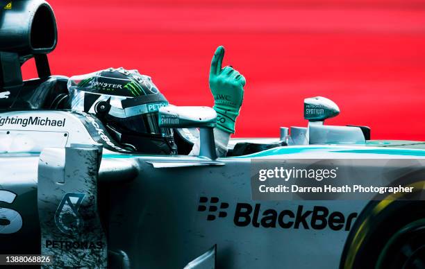 German Mercedes-AMG Formula One racing team racing driver Nico Rosberg driving his F1 W05 racing car while raising his right arm and hand and giving...
