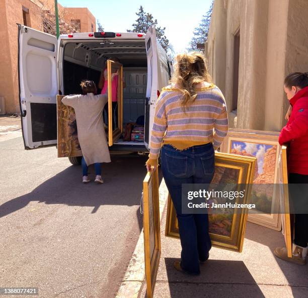santa fe, nm: women moving gallery paintings into van - painted image paintings art stock pictures, royalty-free photos & images