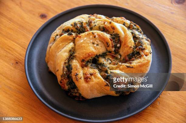 spinach and cheese savory bread scroll on a plate on a wooden table top - braided bread stock pictures, royalty-free photos & images