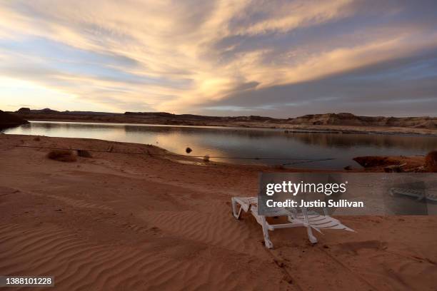 Discarded lounge chair sits on the banks of Wahweap Bay as the sun sets over Lake Powell on March 27, 2022 in Big Water, Utah. As severe drought...