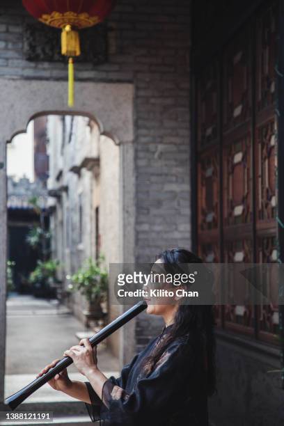 senior asian woman playing shakuhachi flute - shakuhachi stockfoto's en -beelden