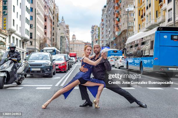 multiracial dance couple poses looking at camera in pedestrian crossing of madrid"u2019s gran vía street - street style in madrid stock pictures, royalty-free photos & images