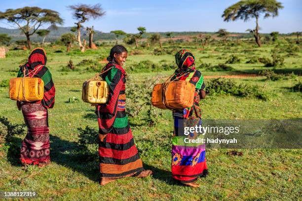 junge afrikanische frauen, die wasser aus dem brunnen, äthiopien, afrika - african girl drinking water stock-fotos und bilder