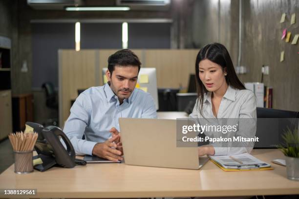 business colleagues chatting they are discussing charts and graphs on laptop computers. - 2 men chatting casual office stock-fotos und bilder