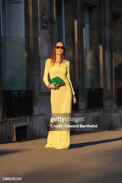 Alba Garavito Torre wears black sunglasses from Ray Ban, gold large pendant earrings, a pale yellow Valensole dress in semi-sheer jersey overlaid by...