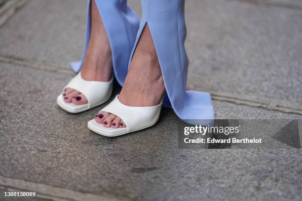 Diane Batoukina wears pale blue slit / split suit pants from The Attico, white latte leather open toe-cap block heels mules / shoes By Far shoes,...