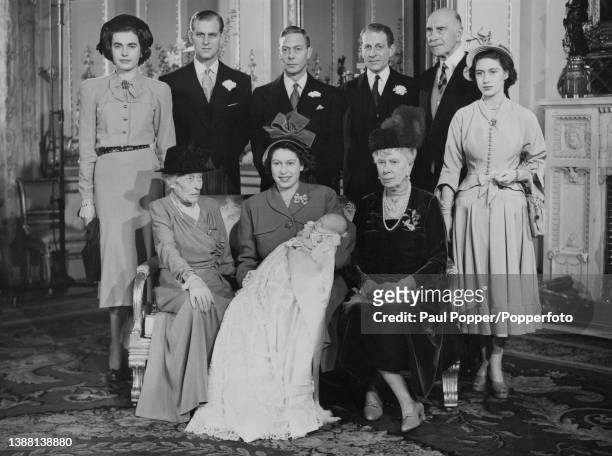 Members of the British Royal Family posed together with Princess Elizabeth, seated in centre, as she holds the infant Prince Charles on the day of...