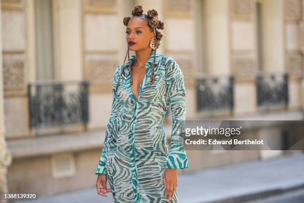 Alicia Aylies wears gold earrings, a white and dark green zebra print pattern buttoned V-neck / long sleeves / midi dress, during a street style...