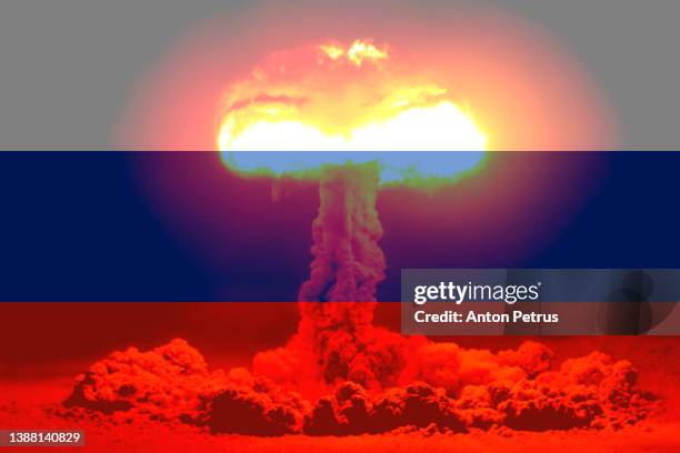 nuclear explosion on the background of the flag of russia. threat of nuclear war - nuklearwaffe stock-fotos und bilder