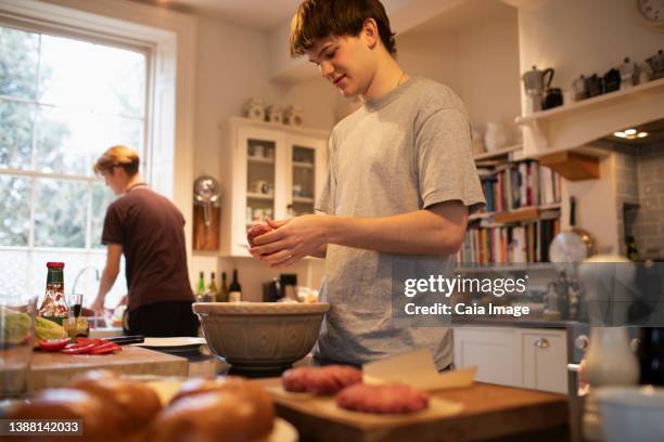 teenage boy making hamburger patties in kitchen at home - boy cooking stock pictures, royalty-free photos & images