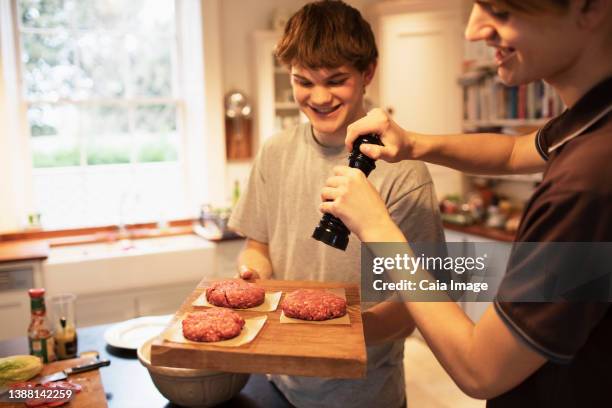 happy teenage boys preparing hamburger patties in kitchen - pepper mill stock pictures, royalty-free photos & images