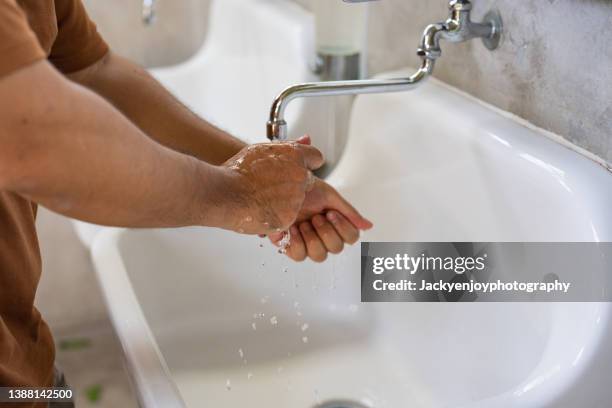 cropped shot of a man maintaining hands hygiene and washing hands with soap in the sink - rubbing hands together stock pictures, royalty-free photos & images