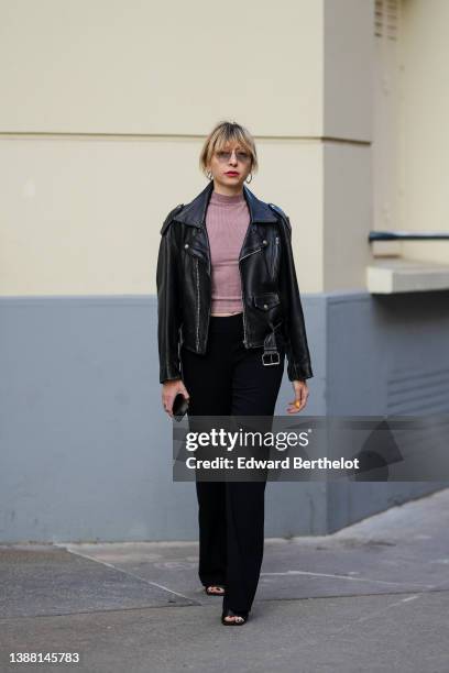 Emy Venturini wears orange sunglasses from Prada, gold and silver earrings, a brown ribbed high neck / cropped top from Helmut Lang, a black shiny...