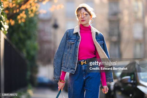 Emy Venturini wears sunglasses from Prada, gold earrings, a neon pink tutleneck / long sleeves pullover from Cos, a blue denim with white sheep...