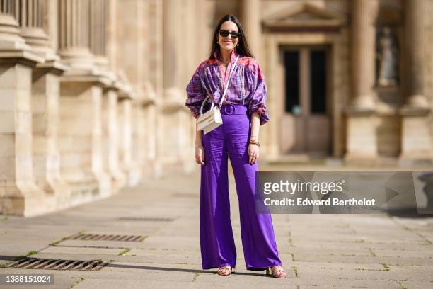Alba Garavito Torre wears black sunglasses from Ray Ban, gold and pearls pendant earrings, a gold chain pendant necklace, a pink / purple / yellow...