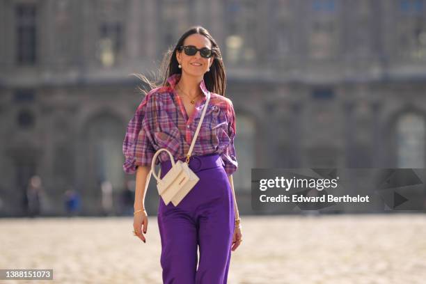 Alba Garavito Torre wears black sunglasses from Ray Ban, gold and pearls pendant earrings, a gold chain pendant necklace, a pink / purple / yellow...