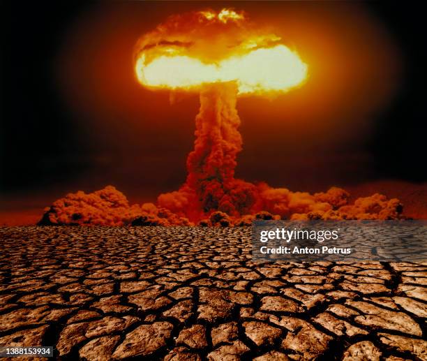 nuclear explosion with mushroom cloud on scorched earth. nuclear war threat concept - nuclear weapon stock-fotos und bilder