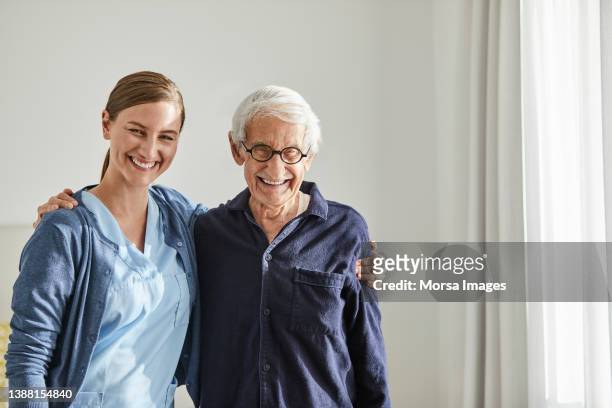 smiling senior man with female nurse - female nurse stock-fotos und bilder