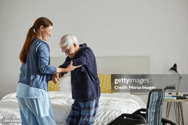 female caregiver supporting senior man in standing - humanity stock-fotos und bilder