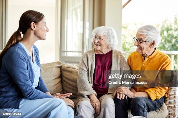 nurse discussing with senior couple at home - group women support doctor stock pictures, royalty-free photos & images