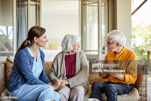 nurse discussing with elderly couple at home - group women support doctor stock pictures, royalty-free photos & images