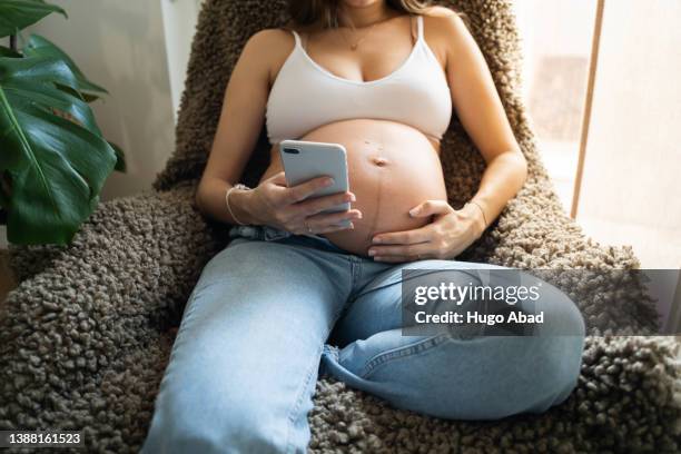 unrecognizable pregnant woman with cell phone. - remplacement photos et images de collection
