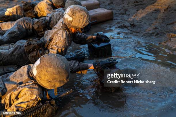 Marine Corps recruits crawl through water as they are run through a simulated resupply effort during a Crucible training exercise on March 25, 2022...