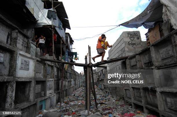 Lifestyle-Philippines-cemetery-poverty FEATURE by Cecil Morella In a picture taken on April 3, 2010 Filipino children cross a bridge over a rubbish...