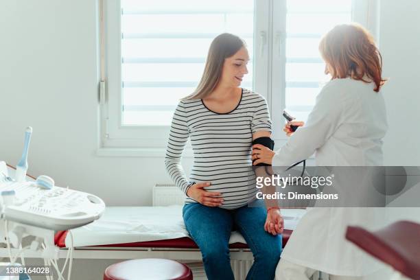 schwangere bei der blutdruckmessung - pregnant woman at doctor stock-fotos und bilder