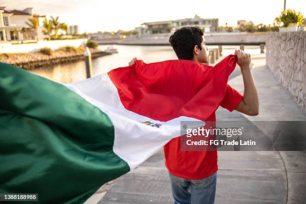 teenage latin boy holding the mexican flag outdoors - soccer flags stock pictures, royalty-free photos & images