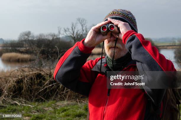 front view of a senior man using binoculars - fleece stockfoto's en -beelden
