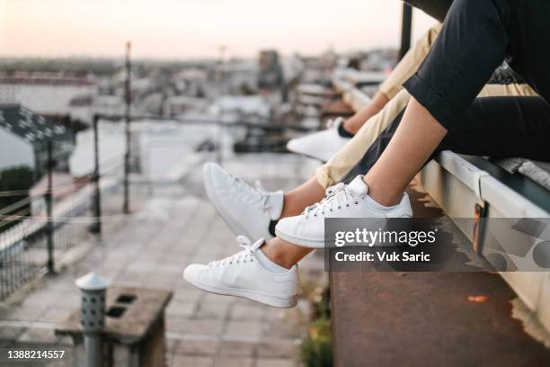 beber cerveza en una azotea y mirar la puesta de sol - running shoes fotografías e imágenes de stock