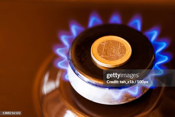 gas stove burner with one euro coin laid on top,burning natural gas - gas prices stock-fotos und bilder