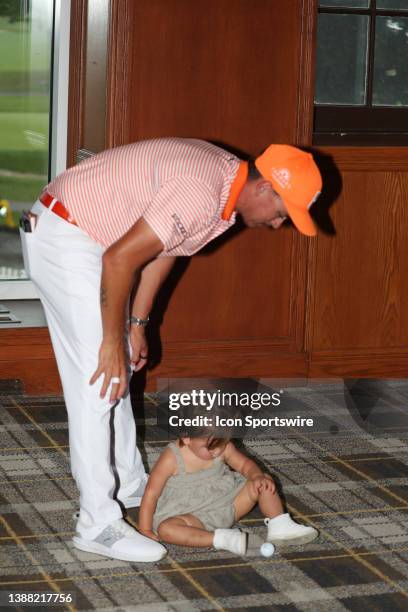 Golfer Rickie Fowler watches as his daughter Maya Fowler plays with the ball that was used for the winning putt on July 2 after the final round after...