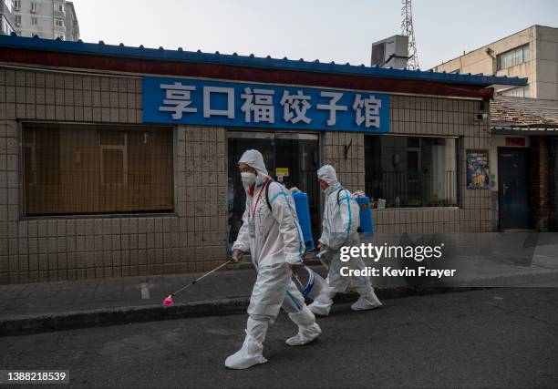 Health workers wear protective suits as they disinfect an area outside a barricaded community that was locked down for health monitoring after recent...