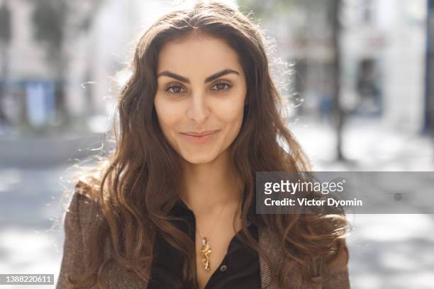 portrait of beautiful lady dressed in a brown coat and black shirt smiling at the camera. - woman long brown hair stock pictures, royalty-free photos & images
