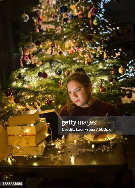 young woman reading in front of christmas tree reading a book,stuttgart,germany - christmas stuttgart stock pictures, royalty-free photos & images