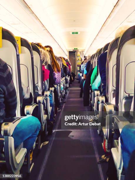 commercial airplane corridor with people sitting. - men bulge imagens e fotografias de stock