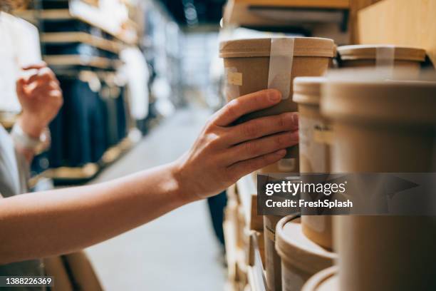 a close up shot of an anonymous caucasian woman in a shop holding a biodegradable package of some product deciding whether to buy it or not - for sale bildbanksfoton och bilder