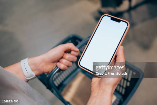 a from above view of an unrecognizable caucasian woman holding her mobile phone while shopping on black friday - basket stock pictures, royalty-free photos & images