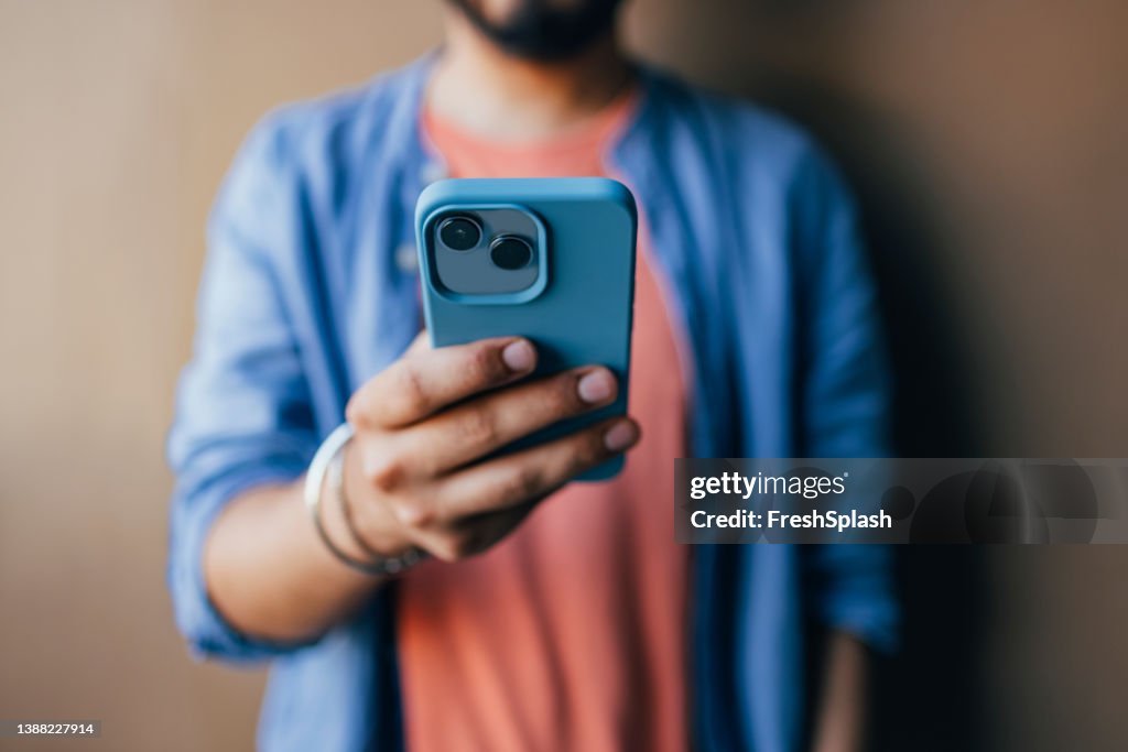 Eine Nahaufnahme eines unkenntlich lässig gekleideten Mannes, der ein Foto auf seinem grünen Handy macht
