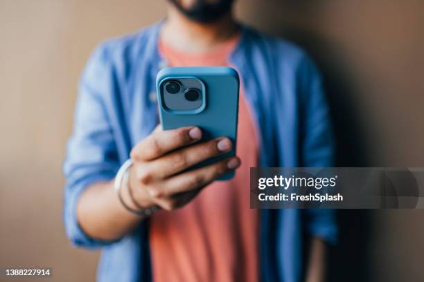 un primer plano de un hombre irreconocible vestido casualmente tomando una foto en su teléfono móvil verde - mensaje de móvil fotografías e imágenes de stock