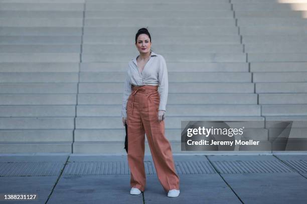 Yvonne Mouhlen seen wearing a creme/beige blouse shirt from Zara, an orange wide leg pants from Jacquemus, a black Prada Re-Edition bag and white...