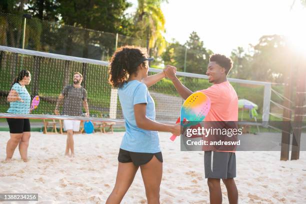 grupo de amigos jogando tênis de praia - tênis esporte de raquete - fotografias e filmes do acervo