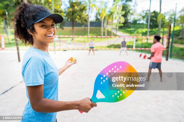 grupo de amigos jogando tênis de praia - batting sports activity - fotografias e filmes do acervo