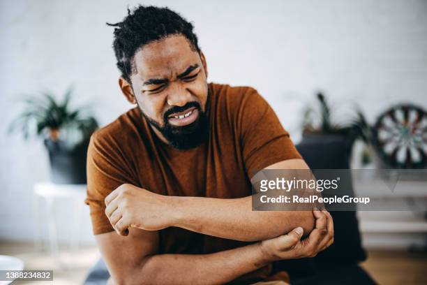 young black man elbow pain - touching elbows stock pictures, royalty-free photos & images