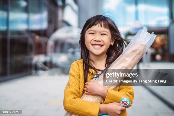 lovely cheerful girl holding a fresh baguette in her arms, smiling joyfully at the camera - ming pao imagens e fotografias de stock