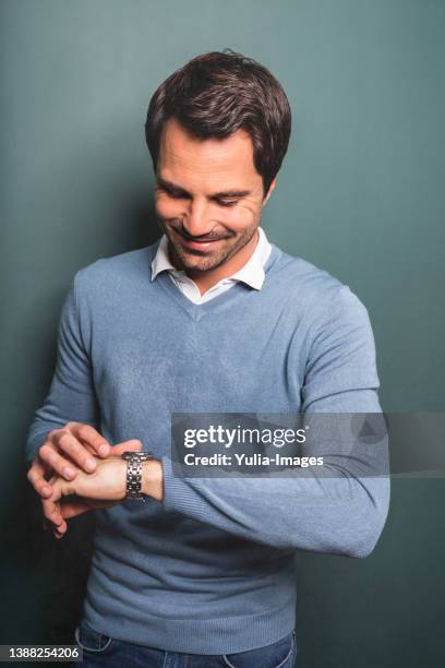 midsection of man checking time against green background - wristwatch imagens e fotografias de stock