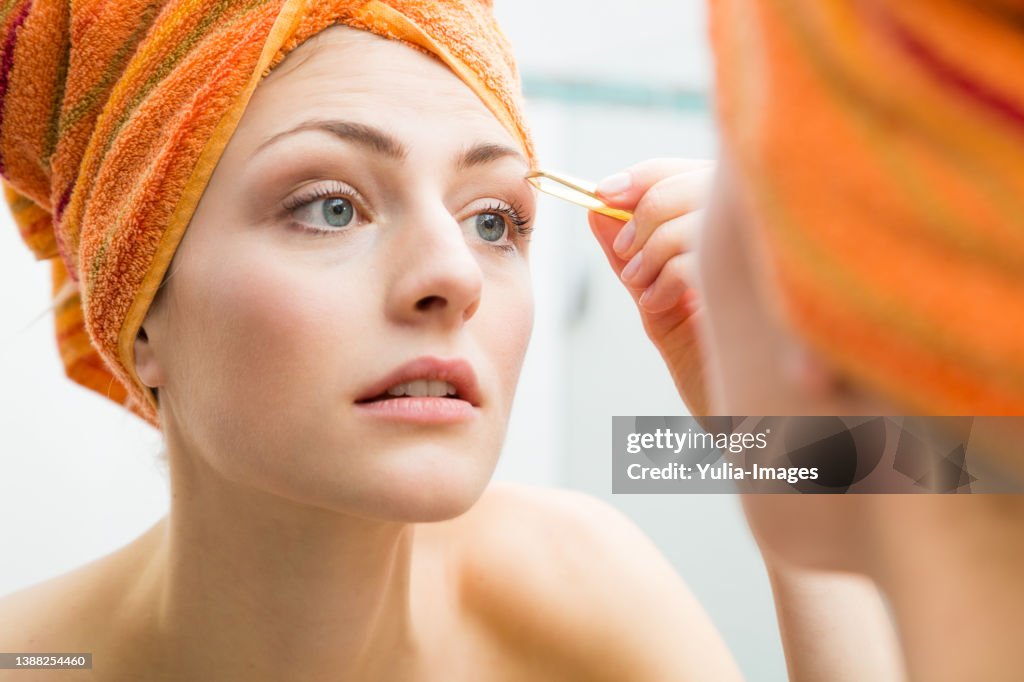 Pretty woman plucking her eyebrows